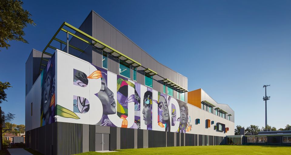 New BUILD Chicago campus, which opened in 2023. Building has mural on the side that says "BUILD" with images of the faces of youth between the letters.